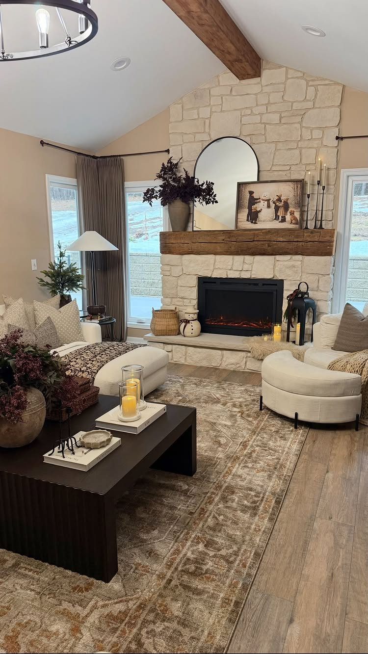 Stone fireplace with wooden mantel in a cozy living room with white armchairs.