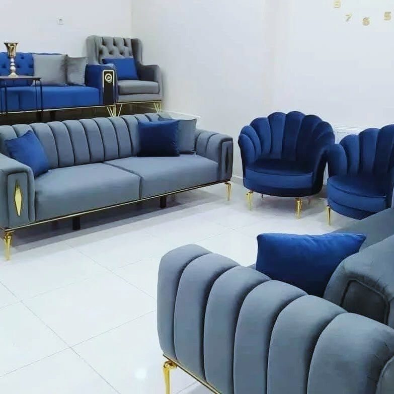 Navy blue and grey velvet sofas and shell chairs in a modern living room.