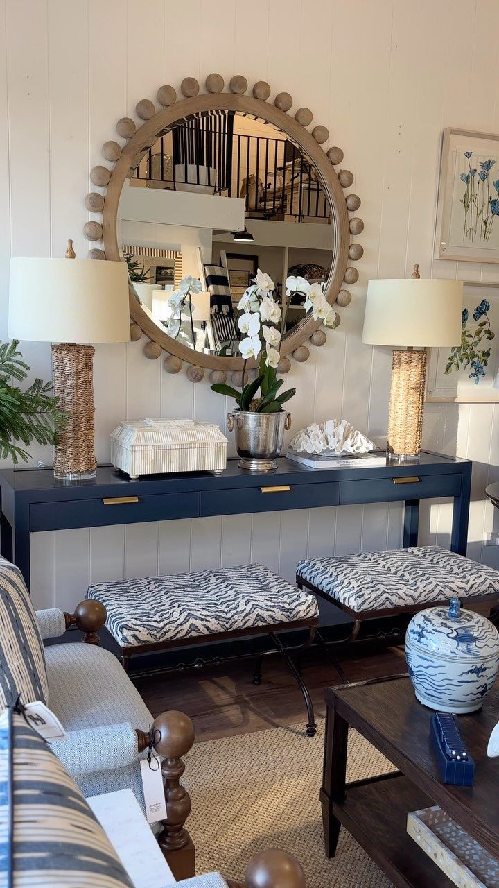 Navy blue console table with brass hardware and a large round beaded mirror.