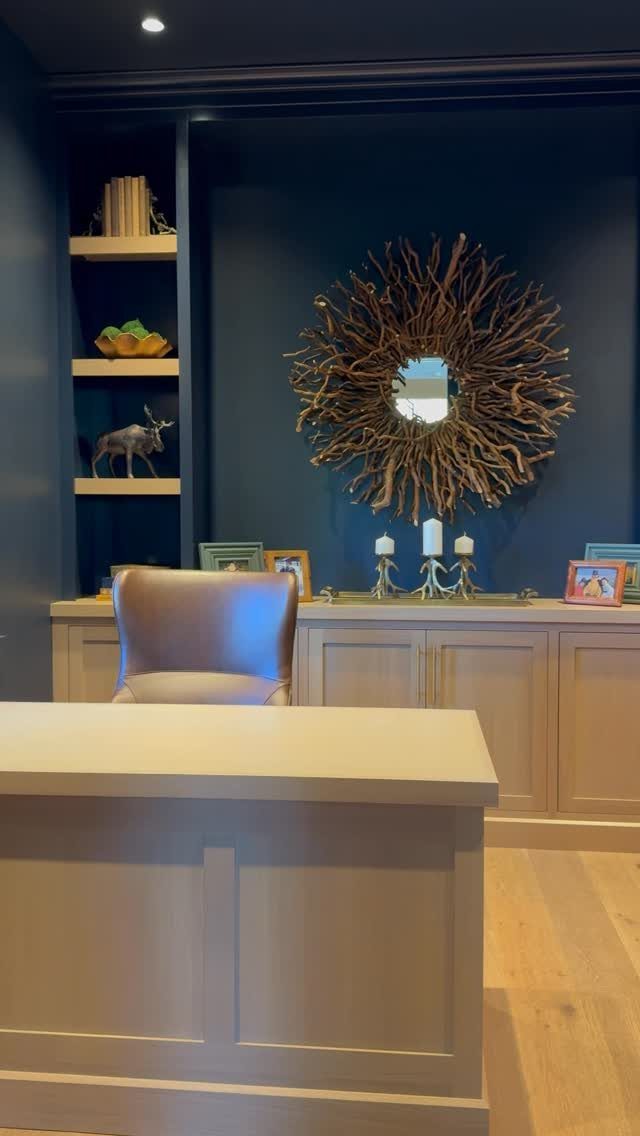 Navy blue built-in shelves and walls with a large sunburst mirror and light cabinetry.