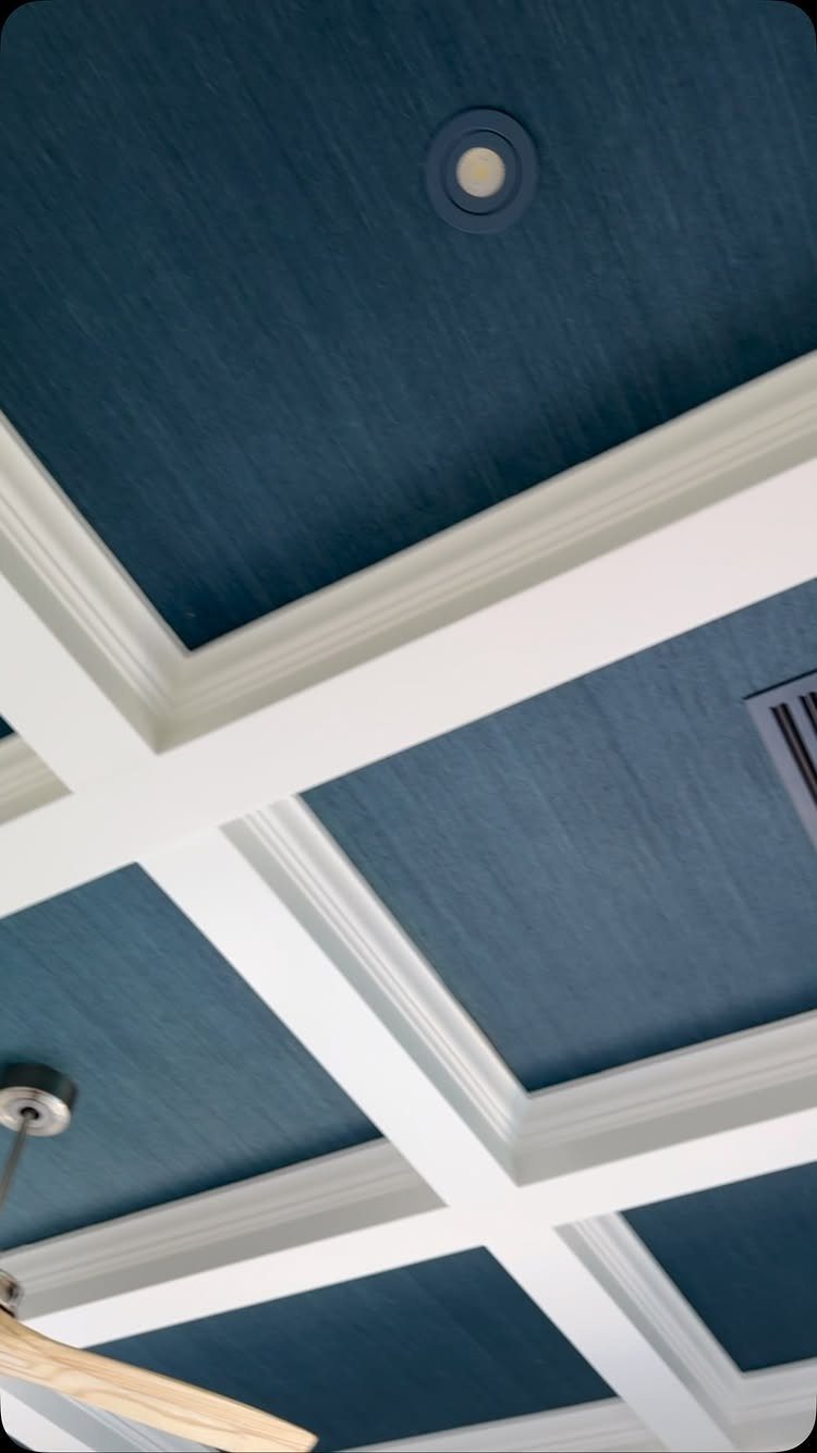 Coffered ceiling with white beams and navy blue painted panels and recessed lighting.