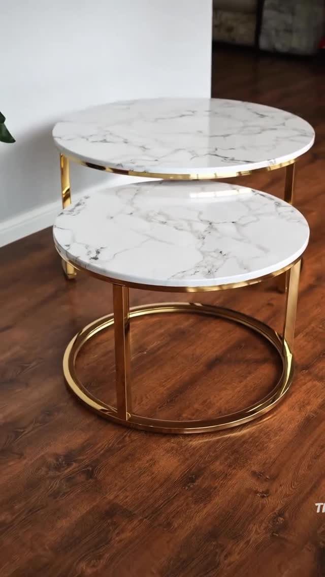 Two round nesting coffee tables with white marble tops and gold metal frames.