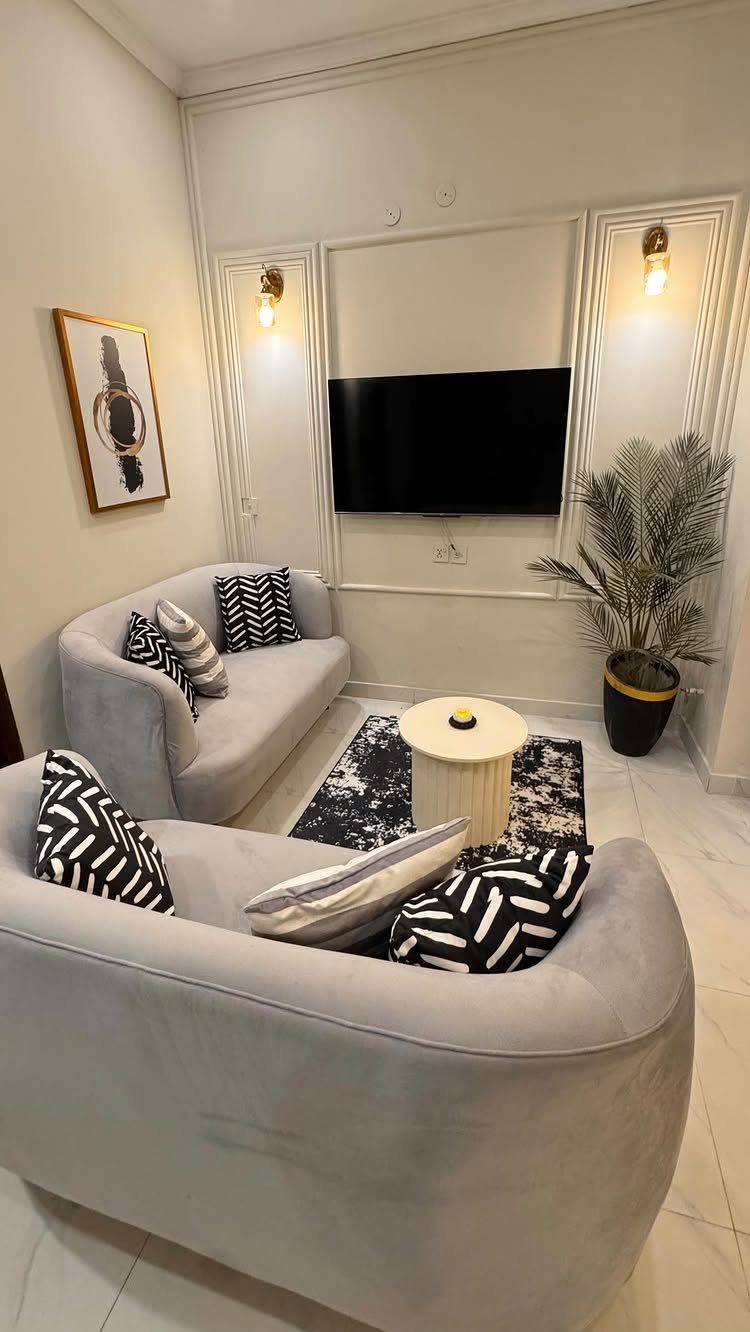 Two light grey curved sofas in a modern living room with a wall-mounted TV.