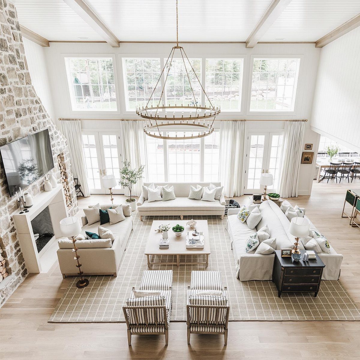 Three light-colored sofas arranged around a coffee table in a spacious, bright living room.