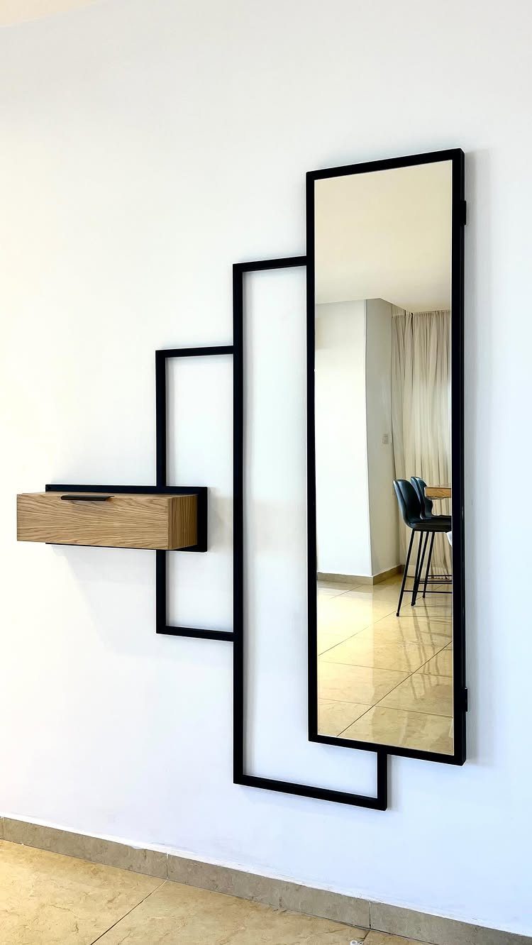Modern wall installation with a tall black framed mirror and small wooden cabinet.
