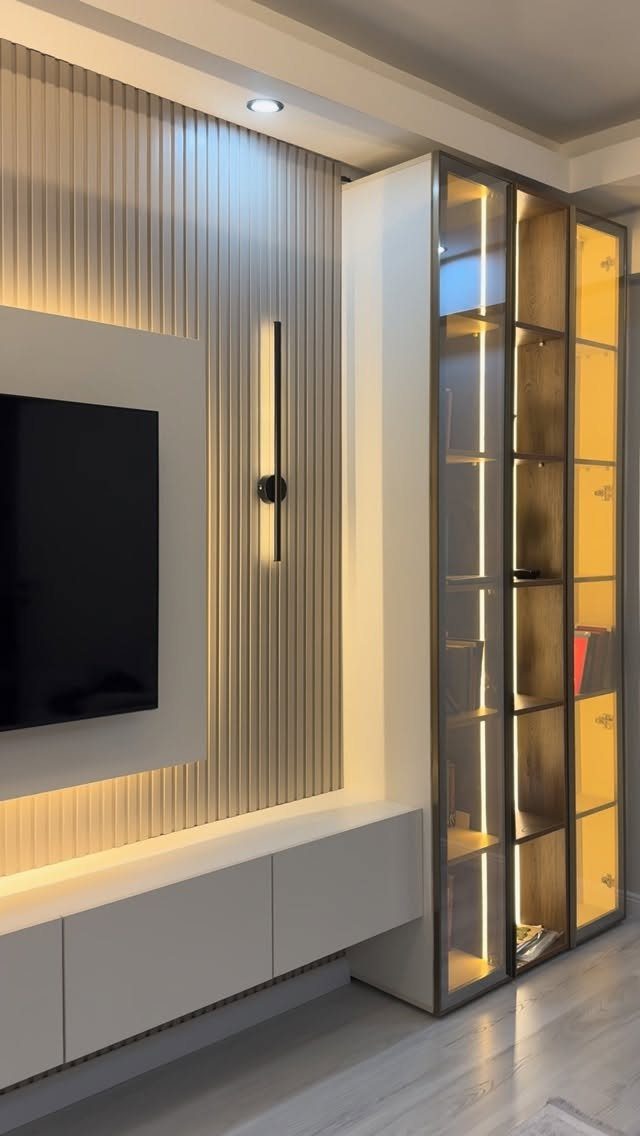Wall-mounted entertainment center with a flat-screen TV, floating cabinet, and illuminated glass shelving.