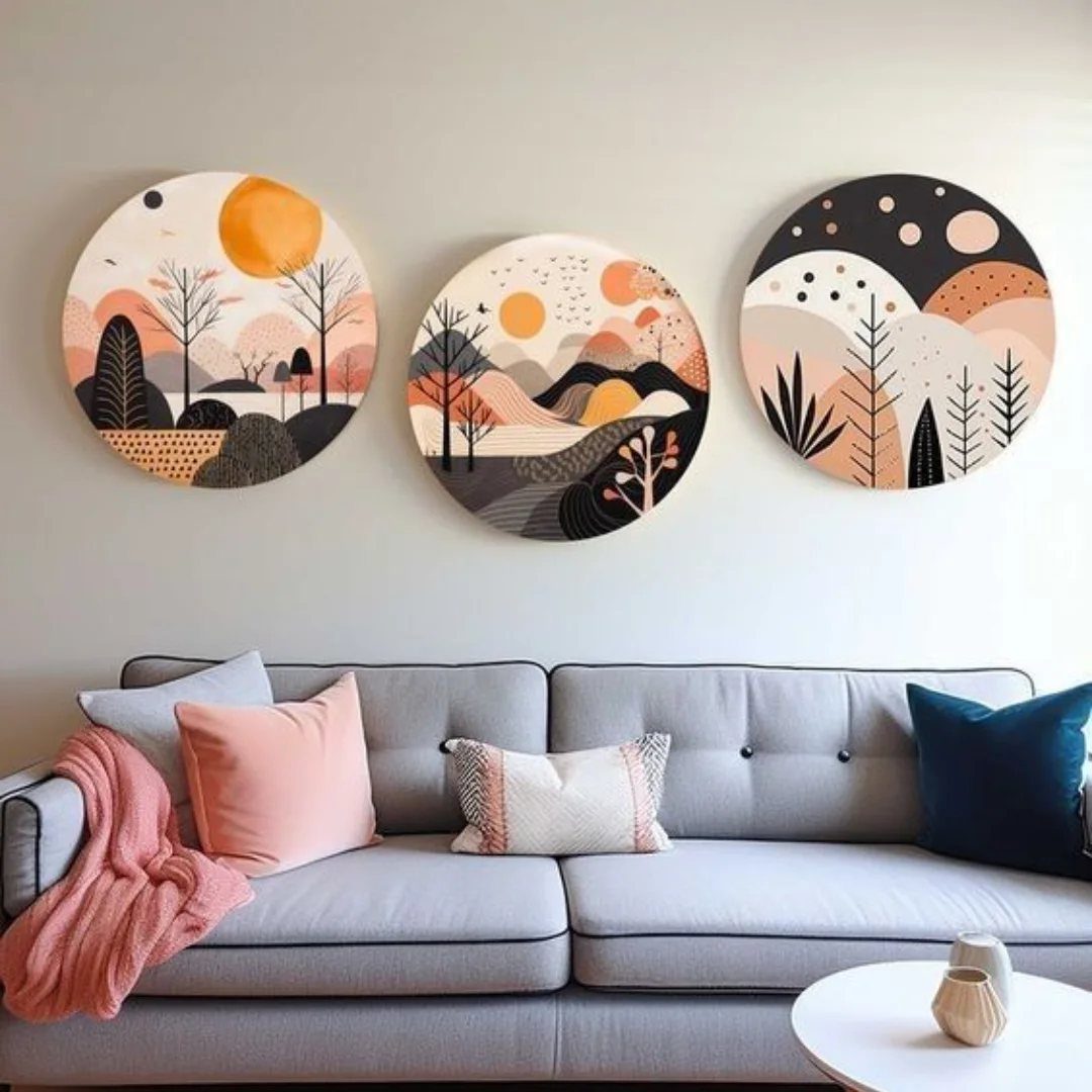Three circular abstract landscape paintings hanging above a grey sofa with colorful pillows.